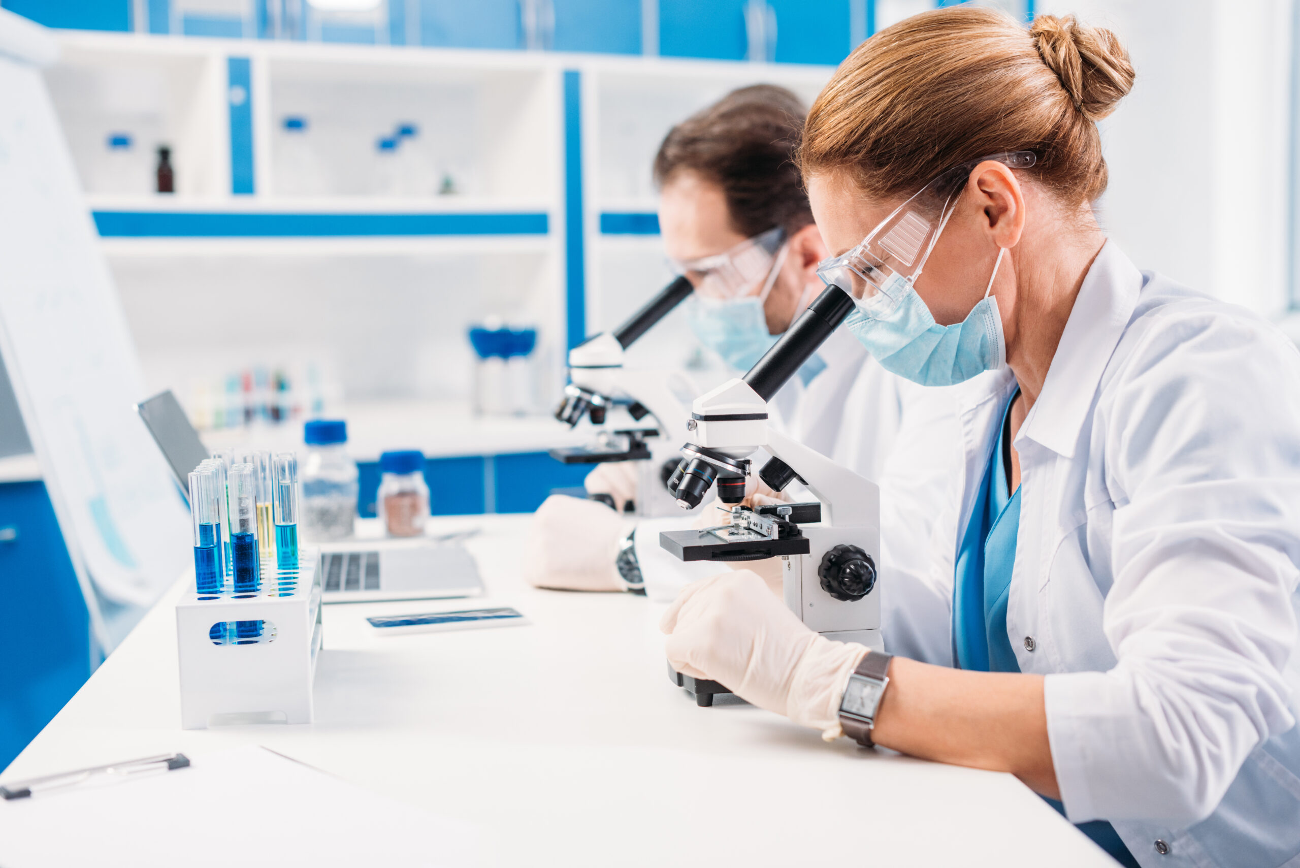 selective focus of scientists in medical masks and goggles looki Women inside a laboratory conducting experiments